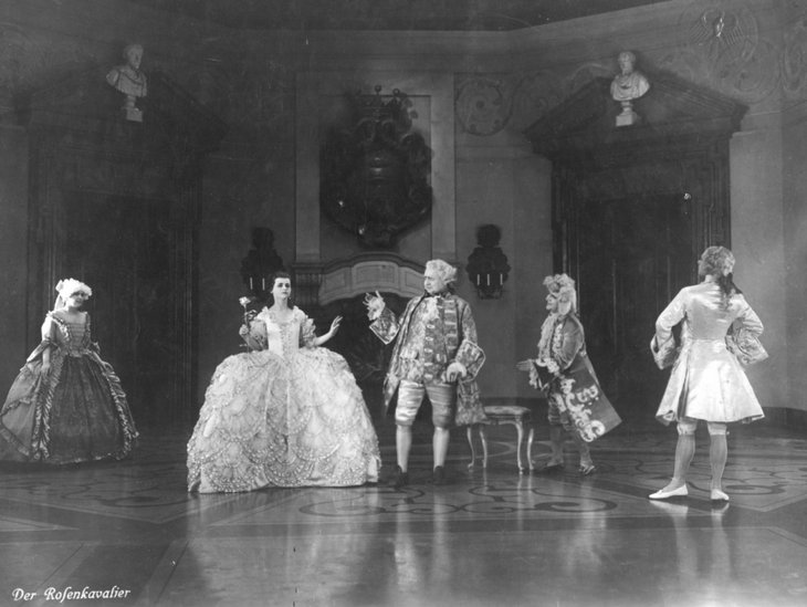 Schwarz weiß Bild aus dem Film Der Rosenkavalier mit fünf Personen in historischer Kleidung